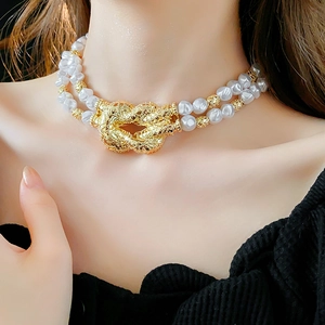Close-up of double-layer necklace with white baroque pearls and textured gold knot detail
