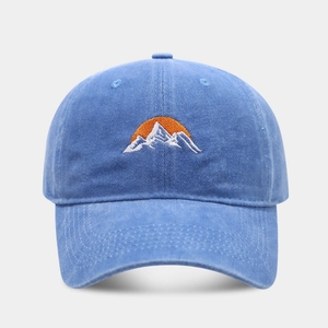 Close-up of blue washed cotton baseball cap with embroidered mountain and sunrise design