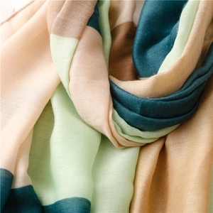 Close-up of color-block woven scarf showing light green, beige, and blue fabric texture