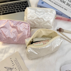 Quilted cosmetic bags with heart and butterfly patterns on a white textured surface