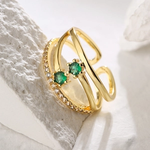 Close-up of gold geometric open ring with green zircon stones and diamond accents