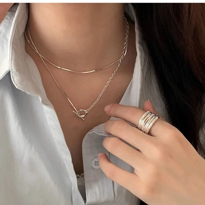 Dettaglio della collana argentata a doppio strato con chiusura OT e anello su modella