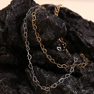 Macro shot of gold and silver heart-shaped chain links on a black stone surface
