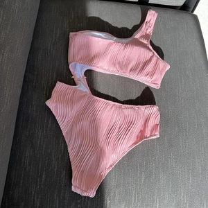 Close-up of pink ribbed fabric on asymmetric cutout one-piece swimsuit with sharp shadows