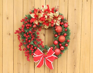 Close-up of Christmas wreath with red berries, pine cones and a white-trimmed red bow