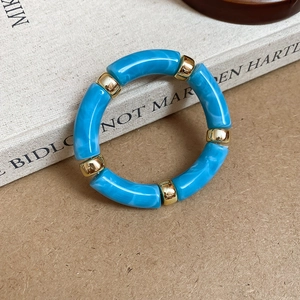 Detail of blue marble resin beads and golden metal spacers on a stylish stretch bracelet