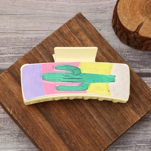 Western style beige hair claw clip featuring a green cactus design on a colorful pattern