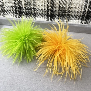 Detailed view of fluffy emerald and golden ostrich feather brooches on velvet tray