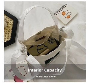 Internal view of a white canvas bucket bag showing main compartment with a mobile phone
