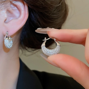 Macro view of silver U-shaped earrings with zircon inlay and secure spring buckle clasp