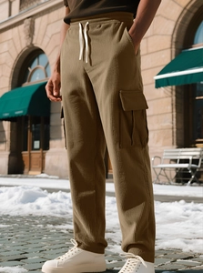 Detail of khaki corduroy cargo joggers for men with multi-pockets in snowy street style