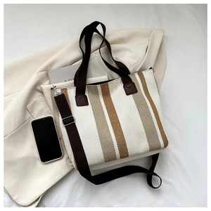 Detailed macro view of striped canvas tote fabric texture and adjustable brown woven strap