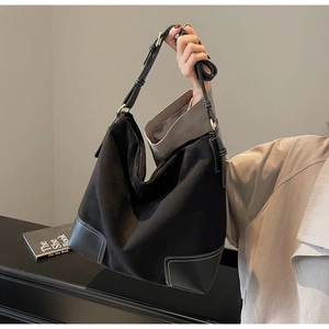 Detail of black suede tote bag with smooth leather stitching and white contrast stitching