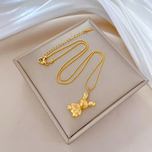 Minimalist titanium steel gold bear pendant necklace on a beige jewelry box