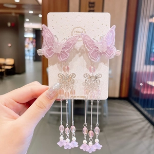 Detail of pink embroidered butterfly hair clips with long silver tassels and beads