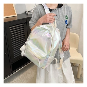 Holografischer silberner Laser-Rucksack am Modell mit einem süßen weißen Teddybär-Anhänger