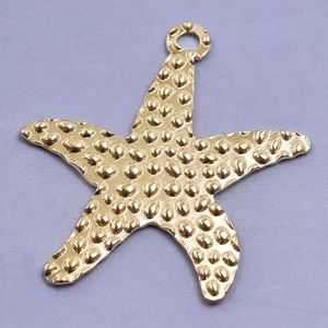 Macro shot of gold starfish pendant with textured metallic surface and top loop