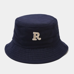 Detailed macro view of white R letter embroidery on dark blue cotton canvas bucket hat