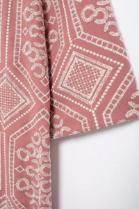 Macro detail of white geometric embroidery on the pink longline cardigan fabric texture