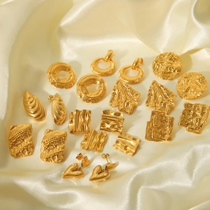 Collection of geometric 18K gold plated stainless steel earrings on white silk fabric