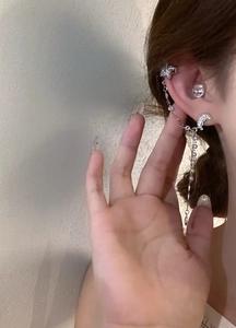Detailed view of elegant star and moon tassel earring with crystal ear cuff on model
