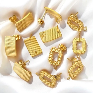 Various textured gold plated stainless steel earring components on white silk background