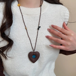 Close-up of heart-shaped stone pendant with blue inlay on beaded ethnic necklace