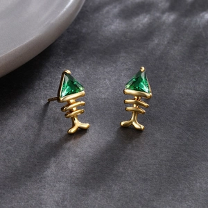 Detailed shot of fishbone earrings featuring 24k gold plating and green zircon stones