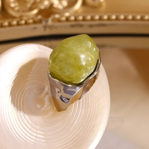 Macro detail of silver textured ring featuring a large irregular green acrylic stone