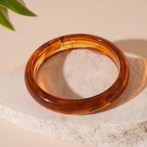 Macro detail of amber resin bracelet with marble texture on natural stone base