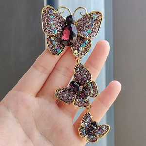 Close-up of triple butterfly brooch with purple rhinestones and golden metal finish