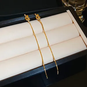 Boucles d'oreilles pendantes à nœud doré dans un écrin noir pour un look de luxe épuré
