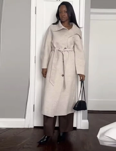 Detail of oatmeal wool coat featuring a waist tie closure and classic notched lapels