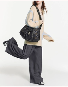 Black vintage leather tote bag detail with distressed finish and metal buckle accents