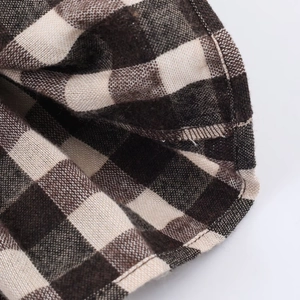 Detailed macro view of brown honeycomb plaid shirt fabric showing reinforced stitching