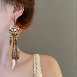 Detail shot of bohemian tassel earrings with bronze metal, beads and natural feathers