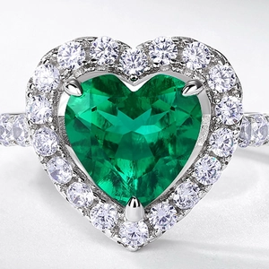 Luxurious heart-shaped emerald ring with halo diamonds on a polished silver band
