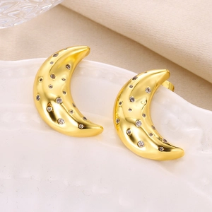 Detailed macro view of gold-plated crescent moon studs with sparkling cubic zirconia