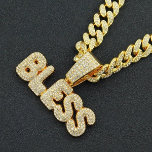 Nahaufnahme der 18K vergoldeten Panzerkette mit glitzerndem 'bless' Buchstaben-Anhänger
