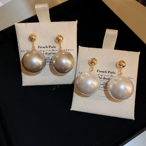 Close-up of white and grey pearl earrings on French Paris card with gold metal plating