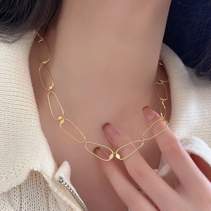 Detail of a minimalist gold irregular oval link chain necklace worn by a female model