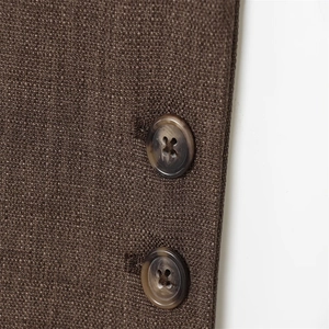 Gros plan sur le tissu texturé marron d'un blazer avec deux boutons naturels