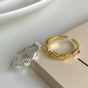 Minimalist 925 sterling silver shell rings in gold and silver finish on a book