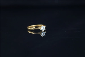 Close-up of a gold solitaire ring with round moissanite stone and its reflection