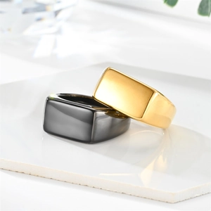 Polished gold and gunmetal rectangular signet rings shown on a marble stone base