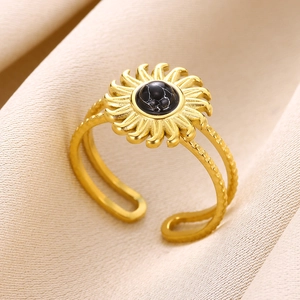 Detail of gold sunburst ring with black marble stone on beige fabric background