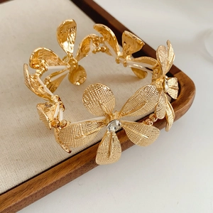 Makroaufnahme von mattgoldenen Blumenarmband mit funkelnden Strasssteinen auf Holz