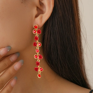 Gros plan de boucles d'oreilles longues dorées avec roses rouges et gemmes sur un mannequin
