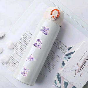 Close-up of decorative watercolor stickers on a white thermos with orange safety lock