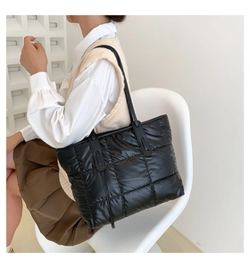 Detail of black quilted puffer tote bag showing soft texture and long shoulder straps